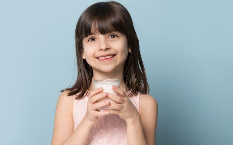 Child smiling and holding a glass of milk